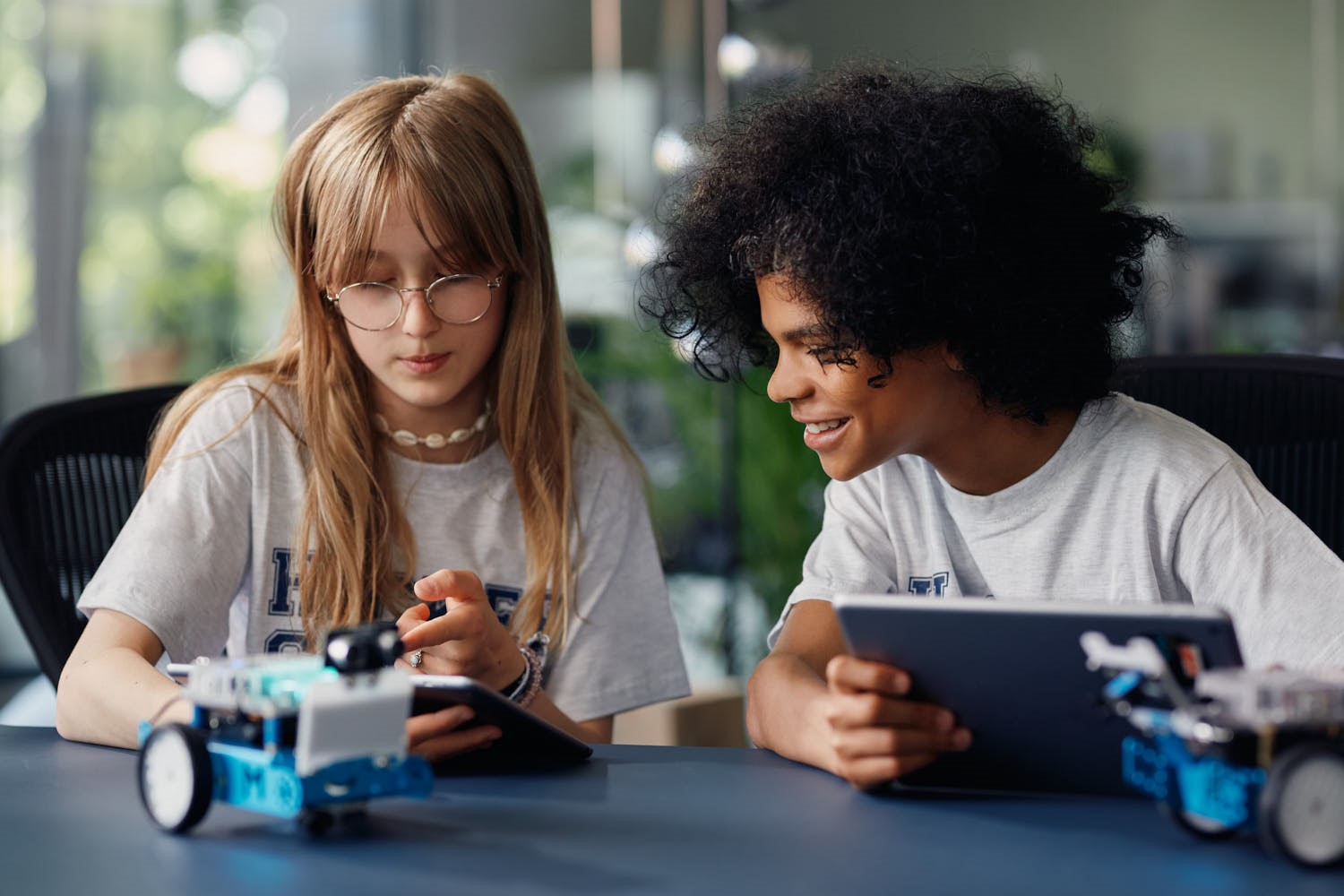  Zwei Kinder aus der Hacker School programmieren zwei kleine Roboter.