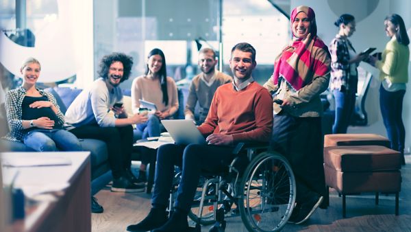 Diverse Gruppe von Menschen sitzt zusammen in einem Co-Working-Space