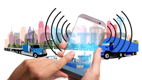 Digitalisierung der Logistik: Zwei Lastwagen vor einer Skyline mit einem Smartphone im Vordergrund