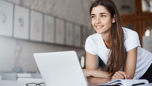 Eine junge Frau, die sich über einen Laptop beugt