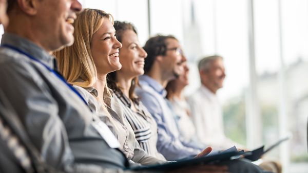 Mitarbeitende sitzen in einer Reihe bei einem Seminar
