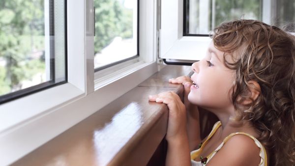 Ein kleines Kind, welches aus dem Fenster schaut