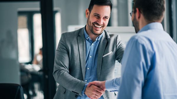 Portrait von jungen, freudigen Menschen, die sich die Hand geben.