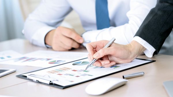 Zwei Personen sitzen an Unternehmensgrafiken.